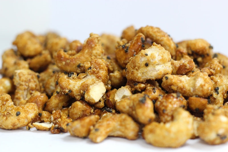 Black Lava Kona Cashews, whole roasted cashews with a dusting of black volcanic sea salt in a loose pile