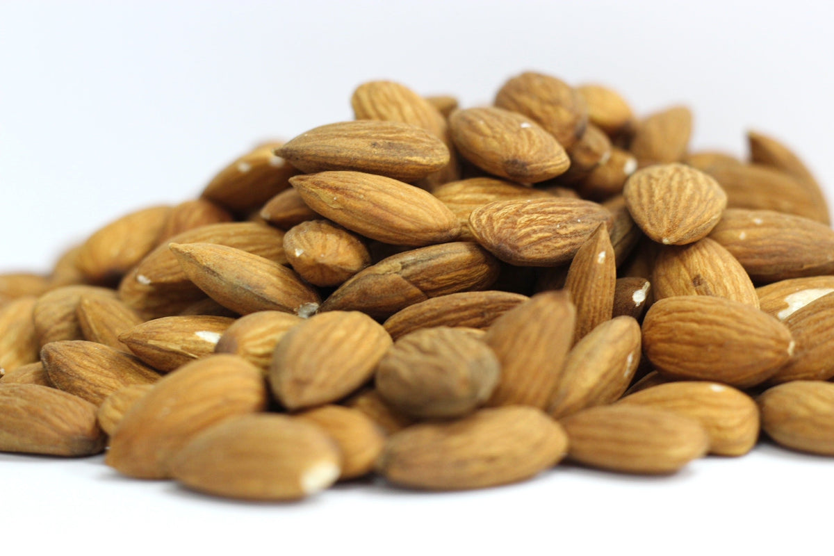 Raw Almonds piled in a loose heap of whole, pale tan almonds