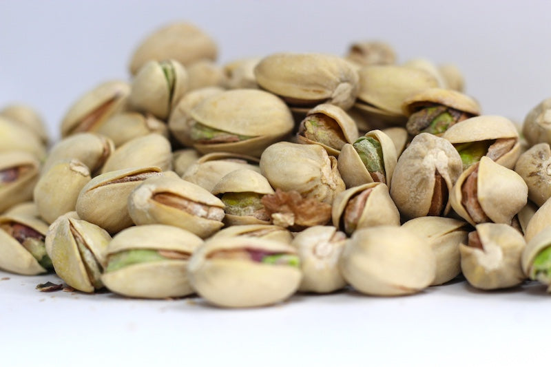 Roasted, Salted Pistachios in a loose heap, showing whole green kernels with pale tan shells