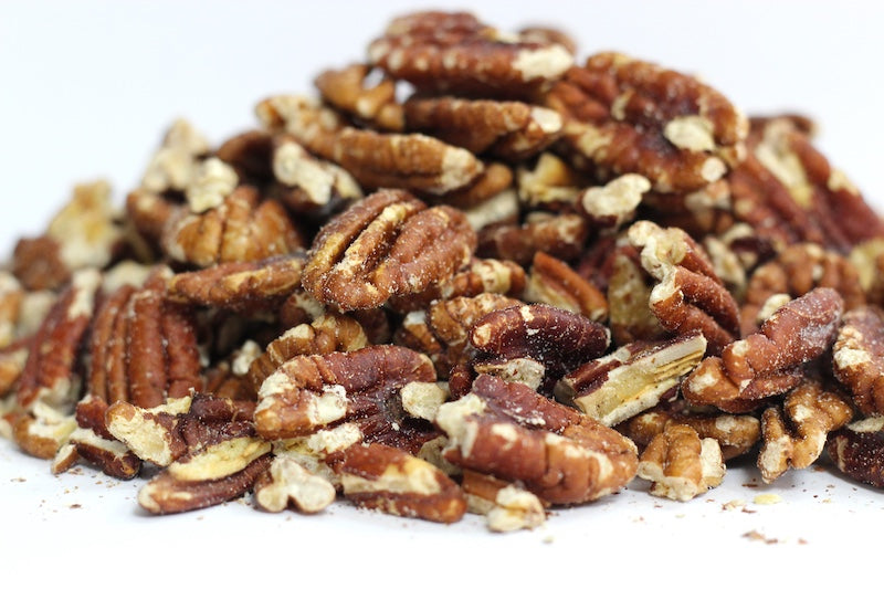 Salted Pecan Halves scattered in a loose heap, showing curved half-nut pieces with ridged surfaces