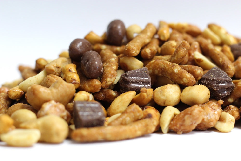 Sea Salt Caramel Cashew Truffle, whole milk chocolate truffles, roasted cashews, peanuts, and honey roasted sesame sticks in a loose pile